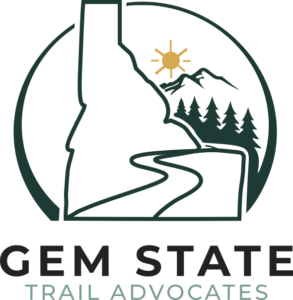 Gem State Trail Advocates Logo including a trail through Idaho, a forest, mountains, and the sun.